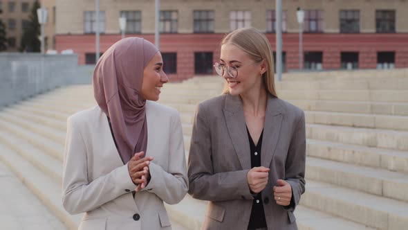 Smiling Young European Caucasian Female Manager Communicating with Indian Girl in Hijab Colleague