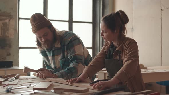 Young Woman Watching Professional Joiner Working in Carpentry Workshop