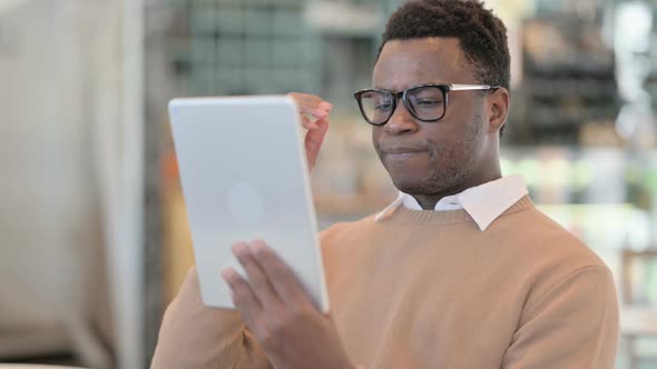 Creative African Man Having Loss on Tablet in Cafe