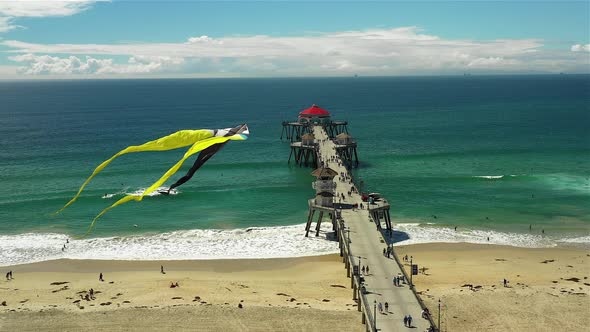 Drone footage of a kite flying over a beach and Pier.