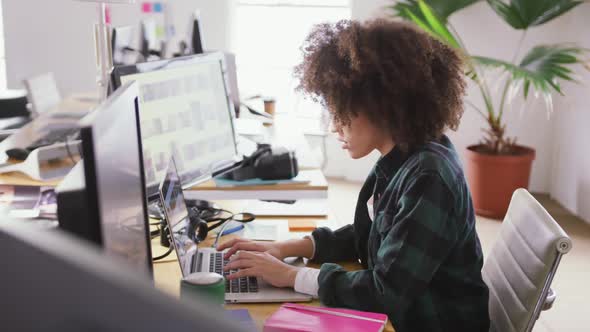 Mixed race woman tapping on computer in creative office