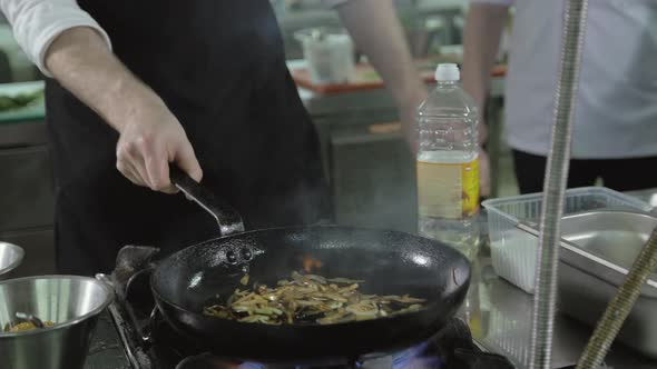 Chef is Making Flambe Sauce on Restaurant Kitchen with Onion and Wine