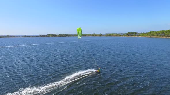 Aerial drone view of a woman kiteboarding on a kite board.