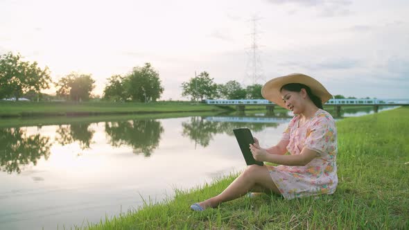 Adult woman sitting on the lawn using portable technology. Portable device tech usage concept.