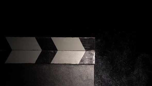 Clapboard with a Cloud of Chalk Dust. Close Up. Black Background