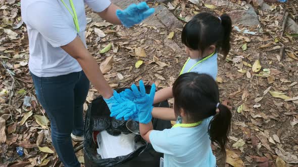 Group of Asian volunteer families put their hands together before picking up trash littered