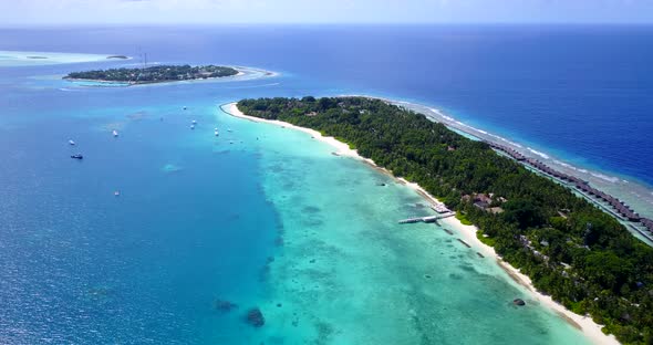 Daytime aerial tourism shot of a white sand paradise beach and aqua blue ocean background in colorfu