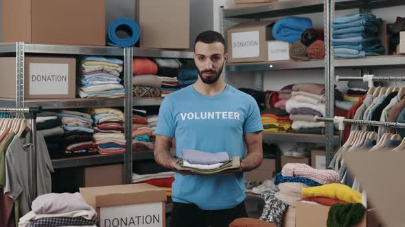 Portrait View of the Caucasian Volunteer Man Holding Clothes and Looking at the Camera with Smile