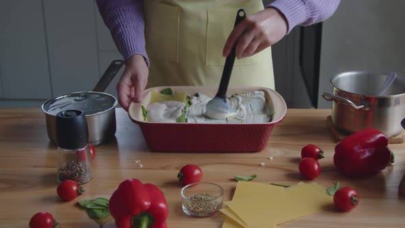 Woman Is Spreading Sauce On Lasagna Noodles