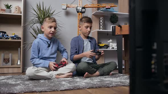 Teen Boys Sitting on the Carpet and Playing Video Game Using Joysticks