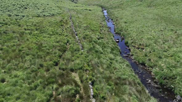 Fast forward tracking aerial along a river and stone wall beside the famous wistmans wood, in the he