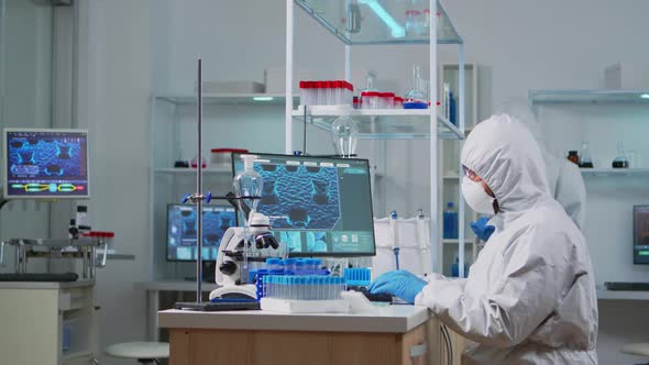 Chemist in Ppe Suit Typing on Computer Checking Virus Development