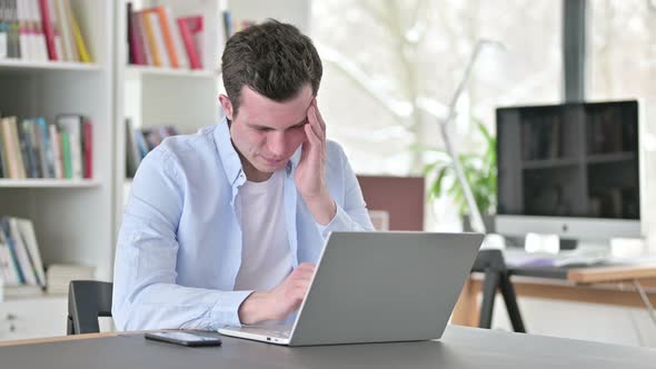 Young Man with Headache Working on Laptop