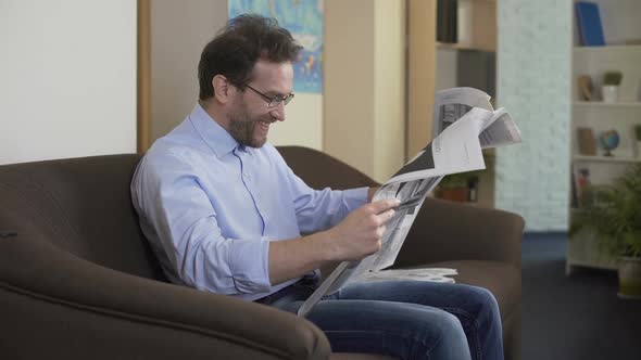 Pleased Man Reading Anecdotes in Newspaper, Free Time and Relaxation at Home