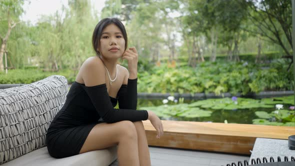 A Girl is Sitting in a Restaurant with Her Hands in Her Lap to Take Photos