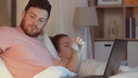 Man in Bed Closing Laptop and Turning Light Off