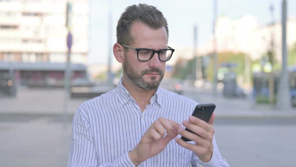 Upset Young Adult Man Reacting to Loss on Smartphone Outdoor