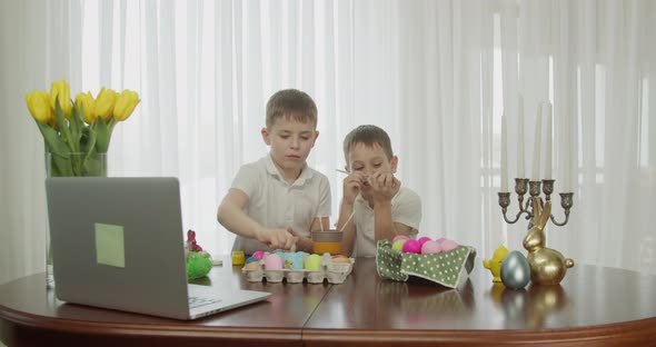 Two Boys Color Their Eggs Looking at the Computer