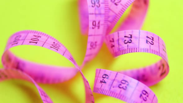 Close Up of a Violet Measure Tape on Yellow Rotating Background