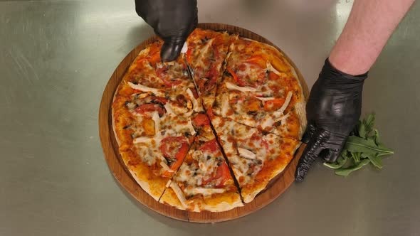 Closeup of the Chef Cutting Pizza with a Round Knife in the Restaurant Kitchen