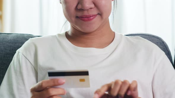 Asian woman using tablet, credit card buy and purchase e-commerce internet in living room.