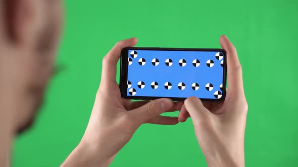Man Holds Smartphone in Horizontal Orientation with Alpha Compositing on Display and Swipes Left