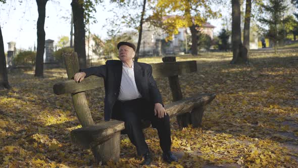 Senior Man Resting on a Park Bench Telling and Looking at the Sky