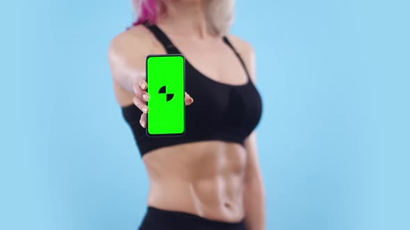 Woman with a Muscular Belly Shows the Phone with an App in the Studio Closeup