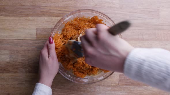 Lady Mixing Her Shredded Carrots With Flour And Eggs In A Round Glass Bowl - static, low angle shot