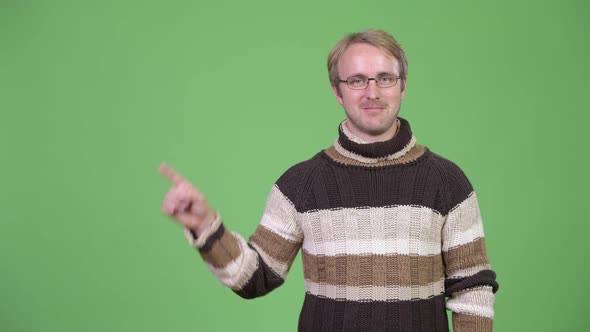 Studio Shot of Happy Handsome Man Thinking While Pointing Up