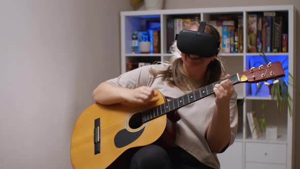 A girl in virtual reality glasses is smiling and actively playing an acoustic guitar