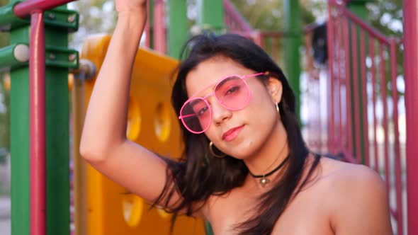 A young woman hipster wearing vintage fashion clothing and retro pink aviator sunglasses and smiling