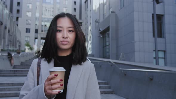 Portrait of a Pretty Young Adult Asian Woman in the Downtown Street with Coffee