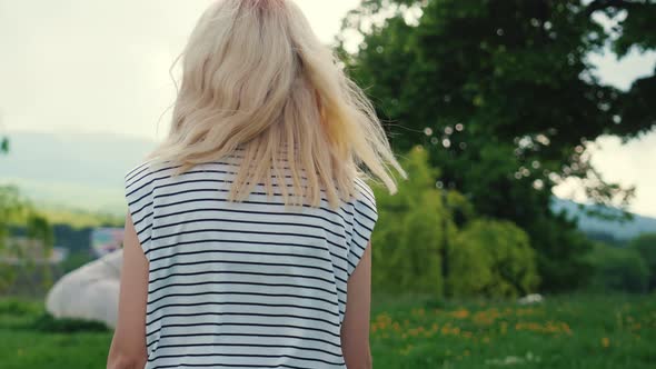 Blond Caucasian Girl Walking in the Park and Enjoying the Green Nature