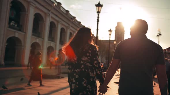 Outdoor Lifestyle Portrait of Young Couple in Love Walking in City on the Street Behind Sunset