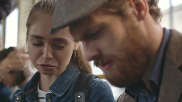 Young Man Showing Picture on Tablet to Woman in Bus