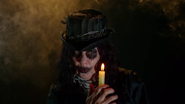 Sinister Old Mature Woman in Carnival Costume of Halloween Witch Making Magic Rituals with Candle