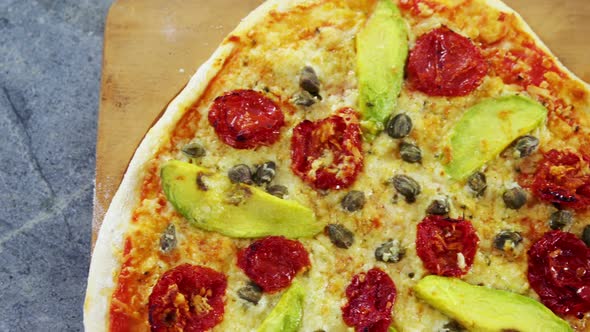 Baked pizza with avocado, cherry tomato and olive toppings