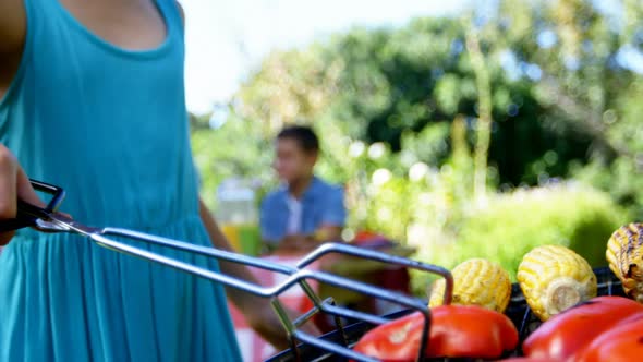 Girl flipping bell pepper on barbecue