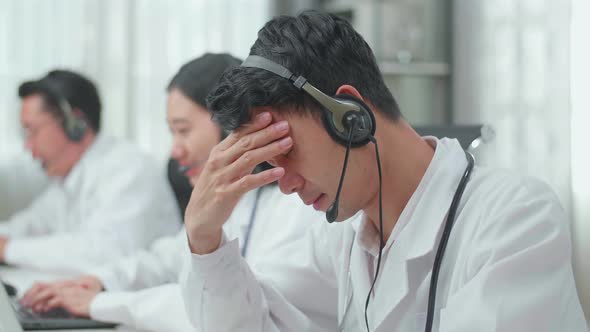 Asian Man Doctor Wearing Headsets Working As Call Centre Agent Head While His Colleagues Working