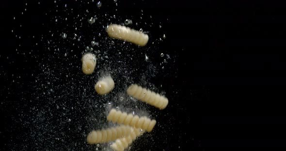 Fusilli Dry Pasta Falls Under Water with Air Bubbles. 