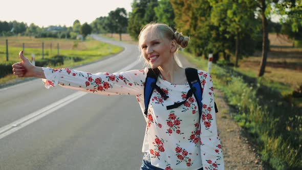 Traveler Woman Hitchhiking on a Sunny Road and Walking