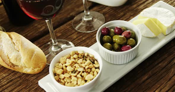 Bowl of peanuts, olives and cheese served with red wine