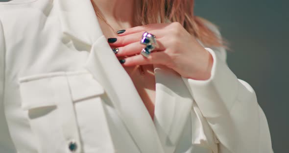 Close Up Model in Trendy White Jacket with Stylish Ring Touching Her Necklace