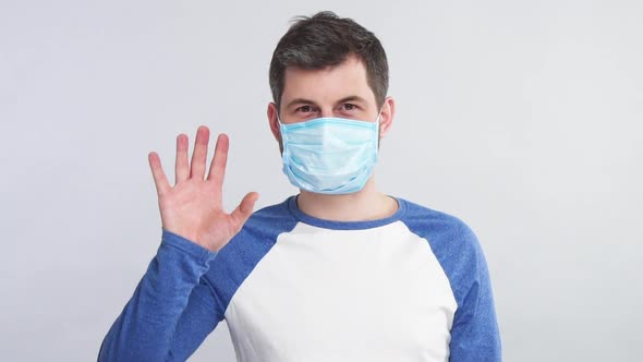 Sick Man in Respiratory Sterile Mask Showing Stop Sign with His Arm To the Camera