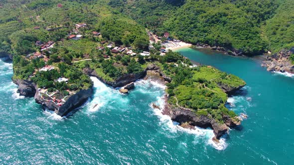 Coastal village in lush tropical greenery on rocky cliff shoreline aerial view