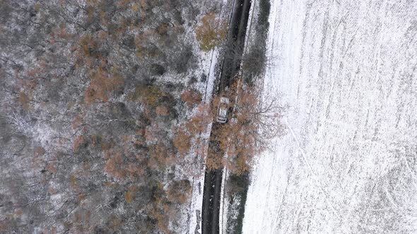 Aerial top view of car driving on snow countryside road - Aerial video of win