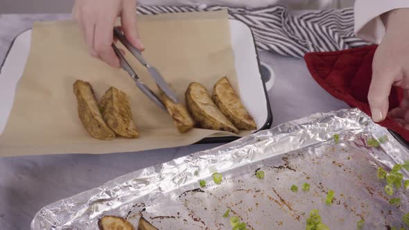 Freshly baked potato wedges with spices on a white serving tray.