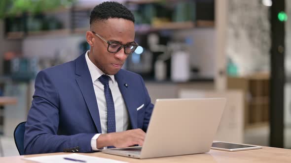 African Businessman with Laptop Smiling at Camera in Office 