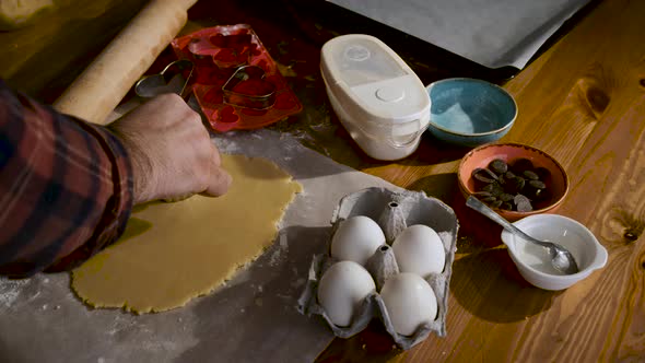 The man who prepares a special occasion cookie. Making cookies in dough with heart molds.